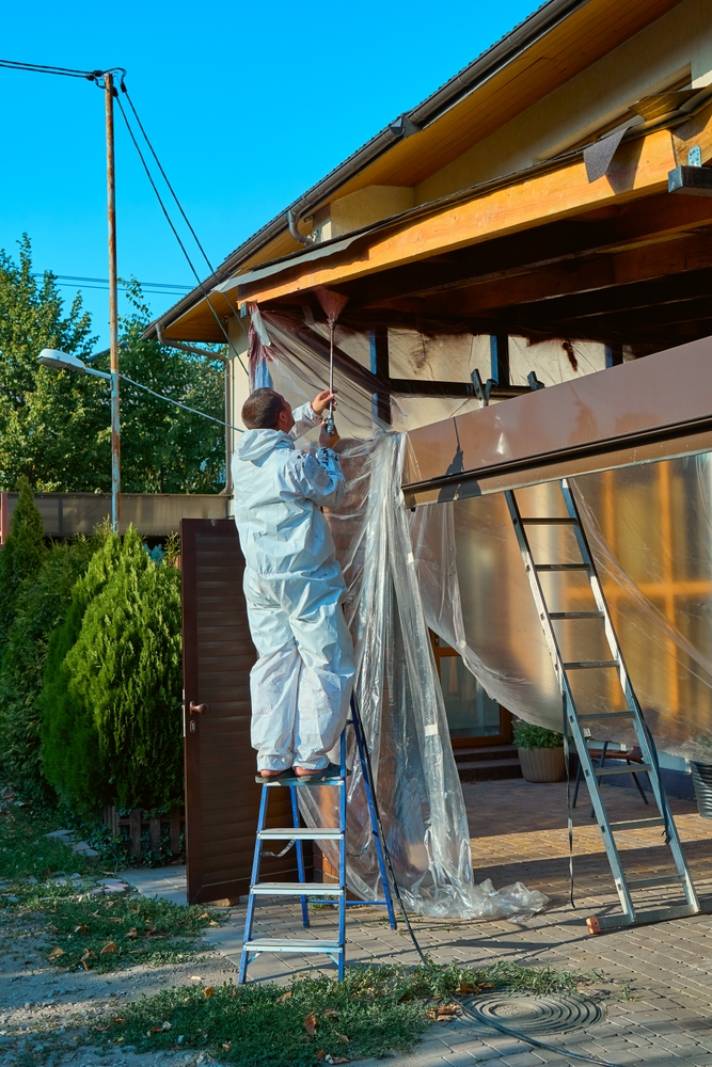 Professional Painting Services In Glebe. A man paints a room with a spray gun.
