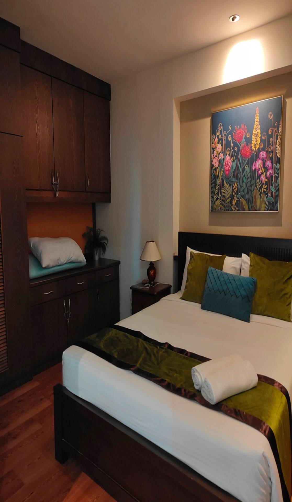 Bedroom Painting In Ottawa. A bedroom scene featuring dark wood furniture, a made bed with pillows, and a floral painting displayed on the wall.